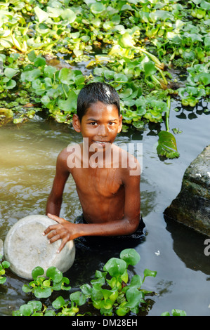 Un jeune garçon indien un pan d'aluminium laver dans la rivière, le Kerala backwaters, Sud de l'Inde Banque D'Images