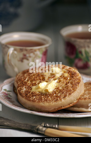 Les crumpets grillés avec du beurre de fusion et d'un plateau en bonnets fleuris avec un sentiment vintage Banque D'Images