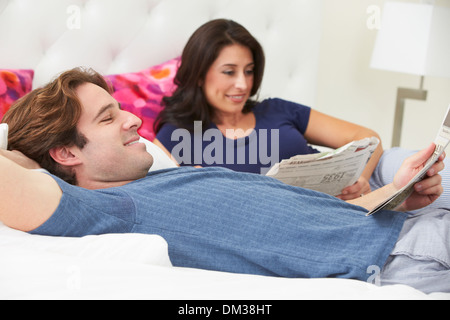 Couple Relaxing In Bed Wearing pajamas et Reading Newspaper Banque D'Images