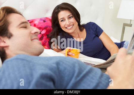 Couple Relaxing In Bed avec café et lire la presse Banque D'Images