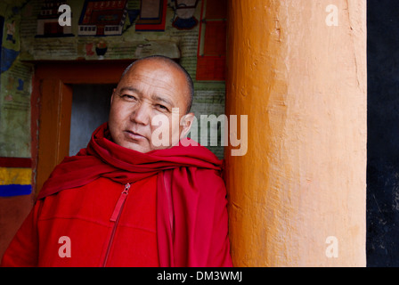 Le Ladakh, Inde - 14 juillet 2009 : un moine bouddhiste dans une corde rouge s'appuie sur une colonne et ressemble à huis clos dans un monastère Banque D'Images