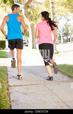 Vue arrière du couple Running on Rue de banlieue Banque D'Images