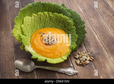 Soupe de potiron dans des feuilles de chou frisé sur fond de bois Banque D'Images