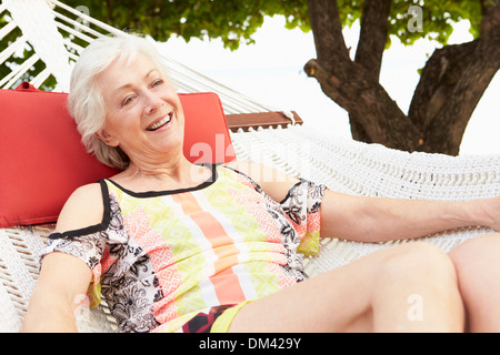 Senior Woman Relaxing In Hammock Beach Banque D'Images