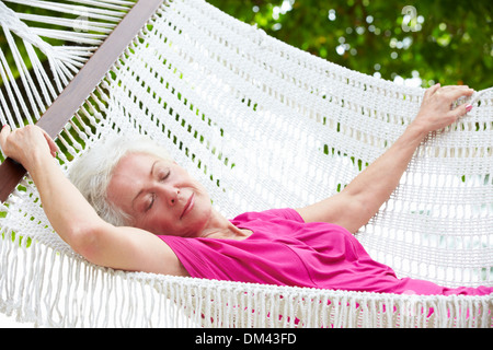 Senior Woman Relaxing In Hammock Beach Banque D'Images