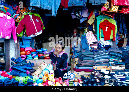 Le Ladakh, Inde - 16 juillet 2009 : une femme assise en attendant le prochain client dans un magasin de vêtements colorés à Leh. Banque D'Images