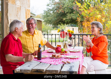 Deux retraités, moi, une femme, à une partie de barbecue arrière-cour. La nourriture sur la table. Les hommes boivent de la bière, les femmes de boire du vin. Banque D'Images