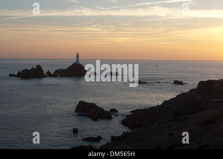 Coucher du soleil par Corbiere Lighthouse sur côte ouest de Jersey à marée haute avec la chaussée sous l'eau. Banque D'Images