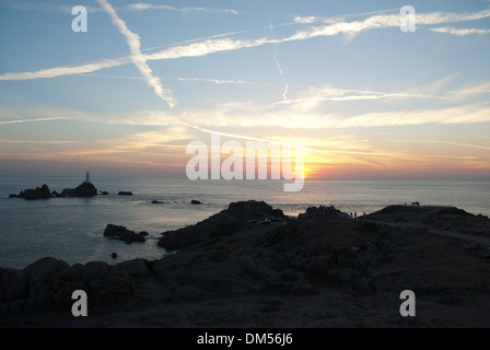 Coucher du soleil par Corbiere Lighthouse sur côte ouest de Jersey à marée haute avec la chaussée sous l'eau. Banque D'Images