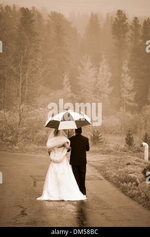 Mariée et le marié une marche sous la pluie parapluie sous Banque D'Images