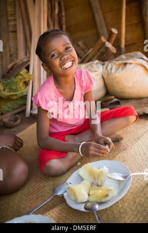 Un enfant consomme du manioc dans le district de Fenerive Est, à Madagascar. Banque D'Images