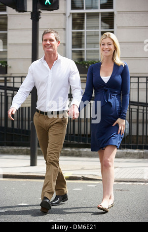 Couple avec femme enceinte Crossing City Road Banque D'Images
