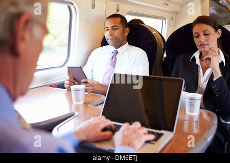 D'affaires pour se rendre à son travail sur le Train and Using Laptop Banque D'Images