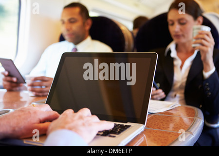 D'affaires pour se rendre à son travail sur le Train and Using Laptop Banque D'Images