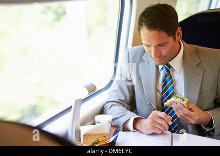 Businessman Eating Sandwich sur Voyage en Train Banque D'Images