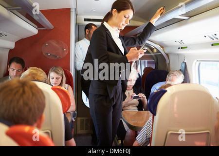 Businesswoman Using Mobile Phone On occupé Commuter Train Banque D'Images