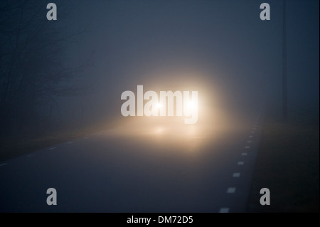 Une voiture est conduite lentement dans la brume sur un soir de décembre dans les Pays-Bas Banque D'Images