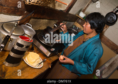 Le Bhoutan, la vallée de Bumthang, woman making sex arra (vin de riz local) avec un verre d'oeufs Banque D'Images