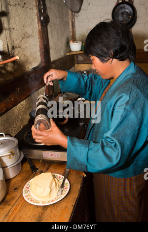 Le Bhoutan, la vallée de Bumthang, woman making sex arra (vin de riz local) avec un verre d'oeufs, verser dans l'arra Banque D'Images