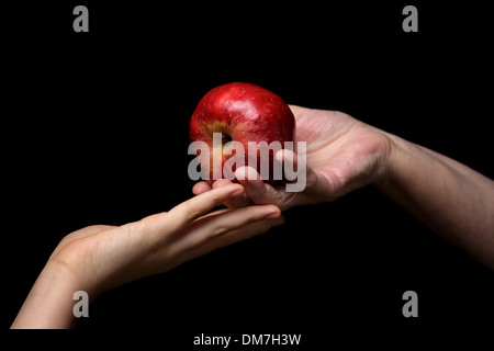 Les mains des femmes, apple donnant isolé sur fond noir Banque D'Images