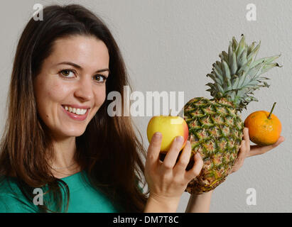 Berlin, Allemagne. Le 05 mai 2013. Une jeune femme est titulaire d'une pomme, une orange et une pomme de pin dans ses mains à Berlin, Allemagne, 05 décembre 2013. Photo : Jens Kalaene - MODÈLE LIBÉRÉ/dpa/Alamy Live News Banque D'Images