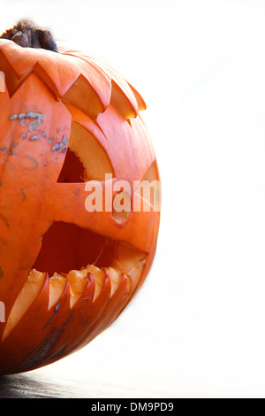 La moitié d'un Halloween citrouille isolé sur un fond blanc. Pumpkin est sculpté d'un typique Halloween face. Banque D'Images