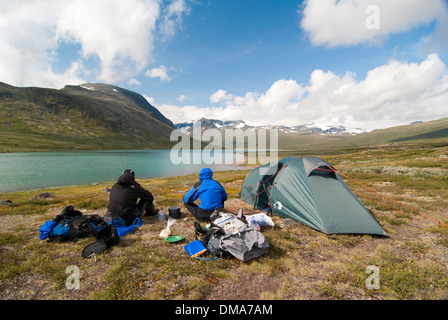 Deux randonneurs s'asseoir sur un lac de montagne, le parc national de Jotunheimen, Norvège Banque D'Images