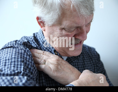 Homme plus âgé grimaces et touche domaine de la douleur dans son épaule Banque D'Images
