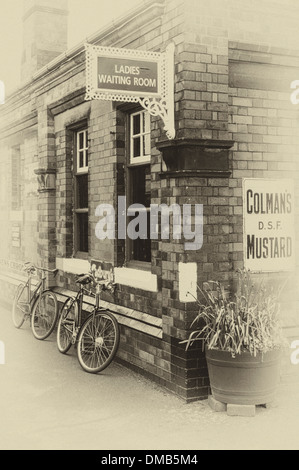 Photo d'un effet antique 1960 scène montrant 2 vélos appuyé contre un bâtiment de la gare. Banque D'Images