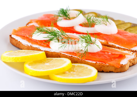 Sandwiches au saumon mariné avec le concombre, l'oignon, l'aneth et citron sur la plaque libre de droit. Banque D'Images