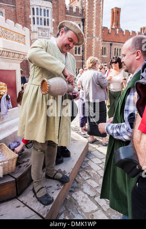 En costume d'acteur sert des verres de vin à l'Henry VIII fontaine de vin de base en cour à Hampton Court Palace. Banque D'Images