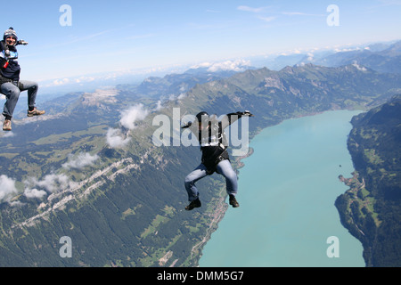 Les parachutistes Freefly sont habillés avec drôle combinaison et sont sit-survolant un paysage de montagne et lac spectaculaire avec 120 MPH. Banque D'Images