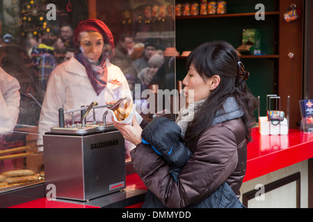 Marché de Noël Allemagne femme prendre la sauce à sa saucisse à Cologne rouleau Banque D'Images