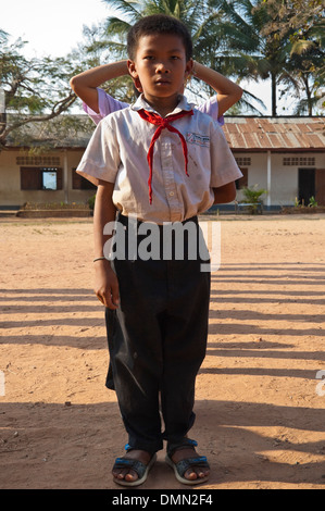 Portrait vertical d'un petit garçon faire une ligne droite à une école au Laos. Banque D'Images