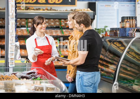 Saleswoman aider dans l'achat de viande de couple Banque D'Images