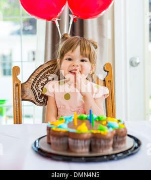 Happy Girl Sitting in front of Birthday Cake Banque D'Images