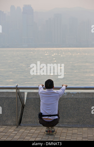 Jogger s'étend sur la promenade de Kowloon, Hong Kong. Banque D'Images