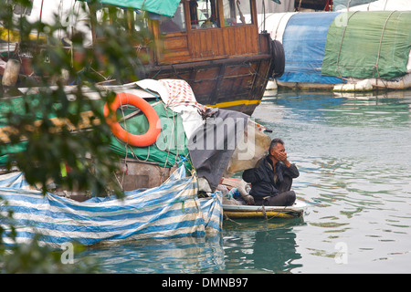 Vieille homme est assis à l'avant d'un petit bateau, Causeway Bay, Hong Kong. Banque D'Images