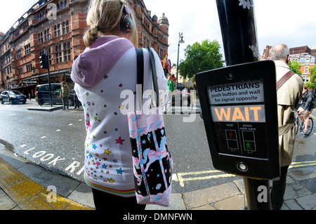 Londres, Angleterre, Royaume-Uni. Jeune femme attendant à un passage pour piétons Banque D'Images