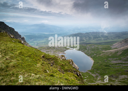 À la recherche du haut de la montagne Cadair Idris dans le parc national de Snowdonia sur Llyn y Gader avec stormy nuageux ciel d'été. Banque D'Images