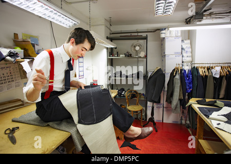 Coatmaker apprenti chez Henry Poole, rembourrage une paire de toiles qui constitueront le corps de la robe. Savile Row, Londres Banque D'Images