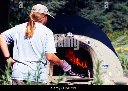 L'homme de travail avec une longue queue de la cuisson du pain à l'ail dans l'air extérieur chauffé au bois s/n Four à l'ail Festival Banque D'Images