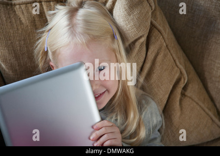 Une jeune fille tenant un ordinateur portable d'argent en face de son visage. Banque D'Images