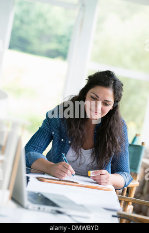 Une femme travaillant à une table à l'aide d'une tablette numérique. Banque D'Images