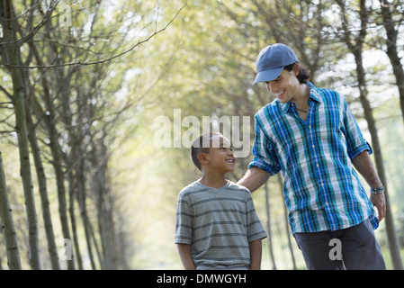 Un homme et un jeune garçon marchant dans une allée d'arbres. Banque D'Images