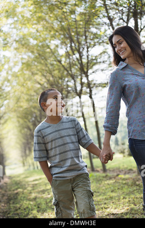 Une femme et un jeune garçon tenant la main la marche dans les bois. Banque D'Images