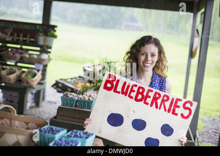 Une ferme de fruits et légumes biologiques. Une personne portant un signe de bleuets. Banque D'Images