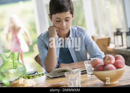 Un jeune garçon en train de lire un livre. Banque D'Images