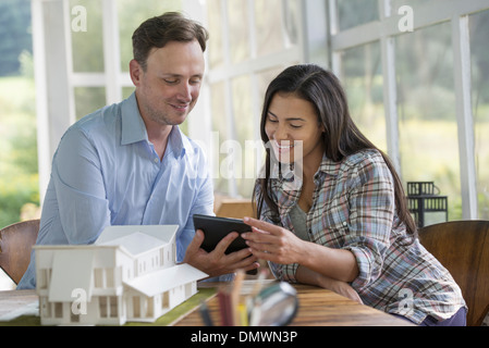 Un homme et une femme à la recherche d'une tablette numérique à la conception d'une maison. Banque D'Images