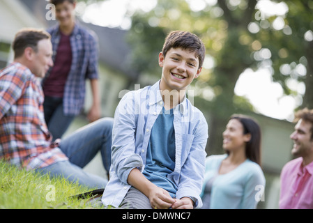 Un garçon assis sur l'herbe en été, pour un parti. Banque D'Images